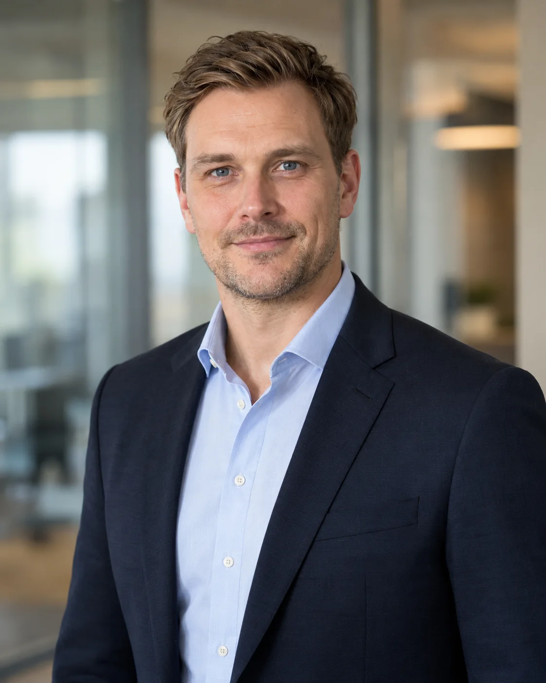 Björn Kiesmeier im Sakko vor einer hellen Glaswand