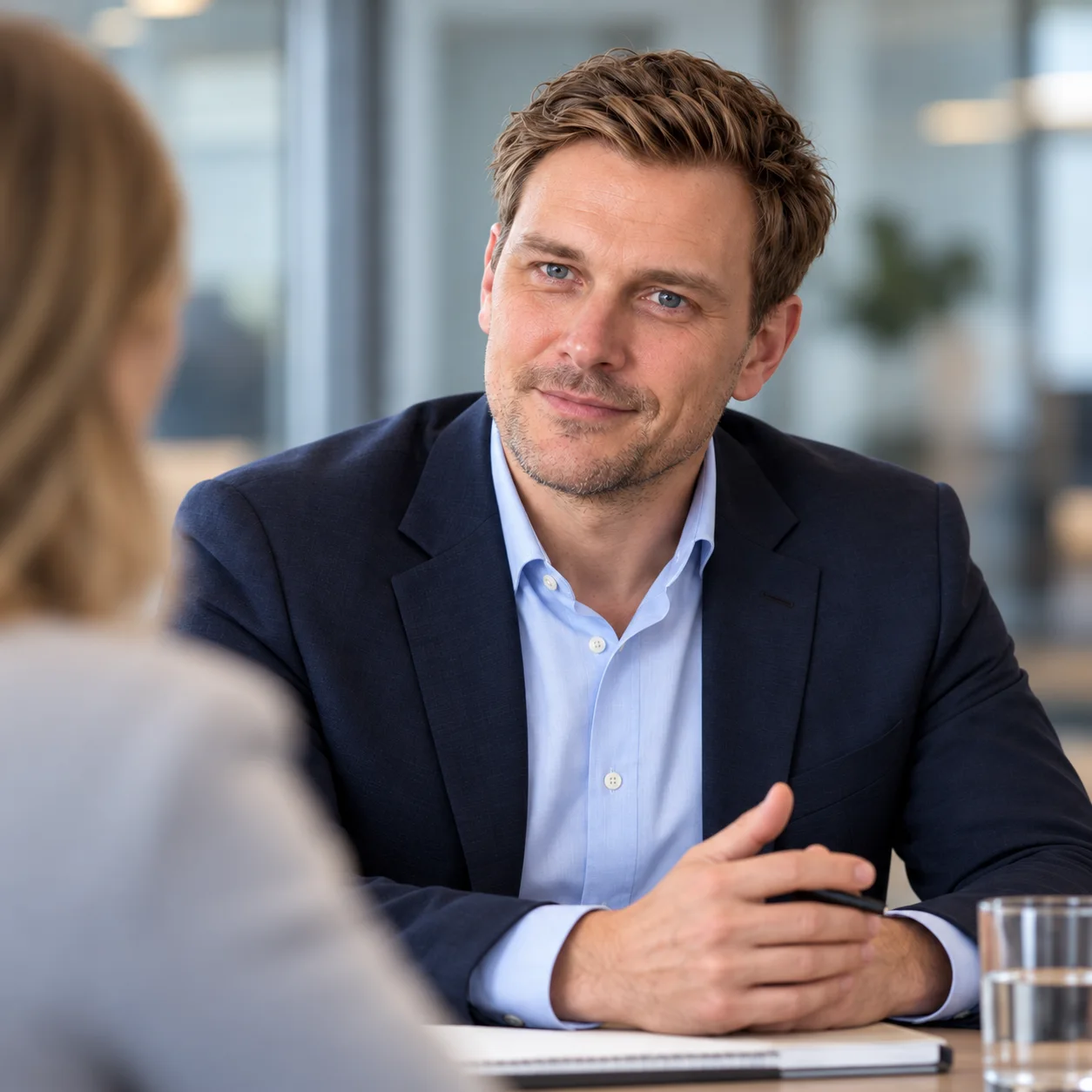 Ein Mann im Sakko im persönlichen Gespräch mit einer Frau am Tisch